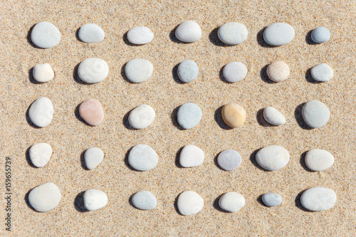 Plakat Pattern of white stones on sand background. Flat lay, top view
