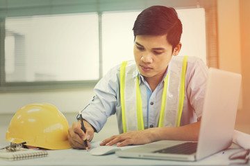 Engineer man working with laptop and blueprints sketching a construction project .Business concept with vintage color.