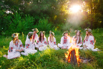 Midsummer. Group of young people of Slavic appearance are sitting around a campfire.