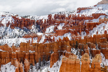 Rugged Landscape Of Bryce Canyon National Park, Utah. The Rugged, Rocky Landscape Of The Valley's Opposite Wall Is Seen With Giant Rock Hoodoos, Pine Trees And A Layer Of Snow.  
