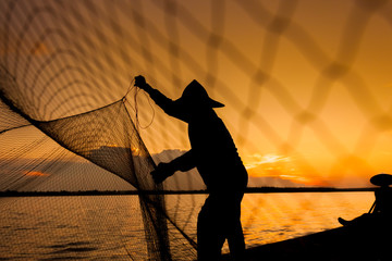 Silhouette,Two fishermen using nets for fishing,sun background 