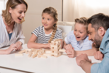 Wall Mural - smiling family playing Jenga game at home together