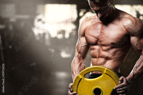 Fotografia Middle aged bodybuilder posing in gym with weight