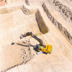 Canvas Print - Aerial view of a excavator in open cast mine or on construction site. Heavy industry from above. Industrial background from drone. 