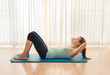 © kieferpix - Woman doing sit up exercise indoors.