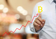 © meepoohyaphoto - hand of businessman touche to symbol of bitcoin in business graph.