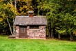 Tiny Stone House. Side view of a tiny stone house with autumn foliage in the yard. This is a historical structure in a national forest and not private property.