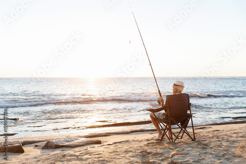 Senior man fishing at sea side Tableau sur Toile