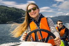 Portrait Of Young And Attractive Woman Close Up Driving The Motorboat, Norway. Beautiful, Ruffled Hair.