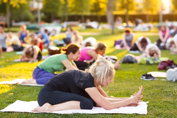 big group of adults attending a yoga class outside in park