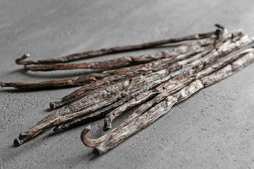 Wall Mural - Dried vanilla sticks on grey textured background, closeup