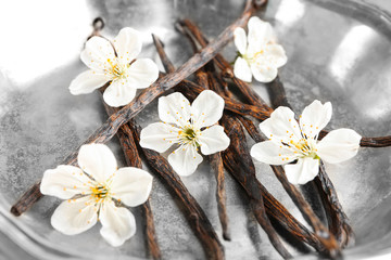 Metal plate with dried vanilla sticks and flowers, closeup