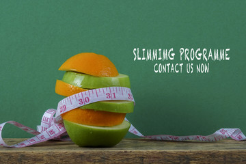 A conceptual fruit of fitness with green apple and orange and a measuring tape.