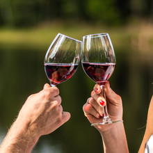 Lovers Clinking Wine Glasses In Nature For The Love. Cheers! Hands Holding Wine Glass. Green Background. Bokeh. Celebration. Wedding. Woman, Man.