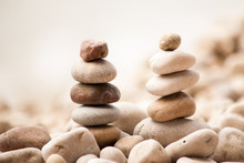 Horizontal Image Of Two Small Zen Pagodas Of Five Pebbles Against A Blurred Background Of Sea And Pebble Beach
