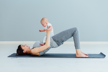 Wall Mural - young mother does physical yoga exercises together with her baby boy