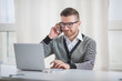 © bokan - Young man at the workplace using smartphone and laptop