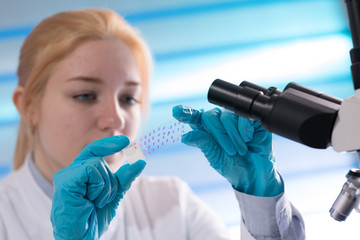 Wall Mural - Doctor woman working  a microscope. Female scientist looking through a microscope in lab. Student girl looking in a microscope, science laboratory concept