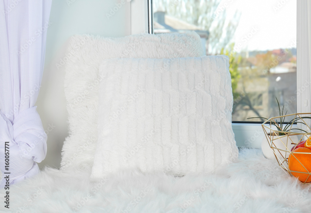 Pillows and warm  plaid on a window sill with fruits