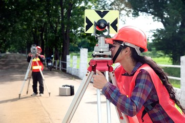 Surveyor or Engineer making measure by Theodolite with partner on the field.