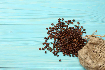  coffee beans in sackcloth on blue wooden background. With copy space. Top view.