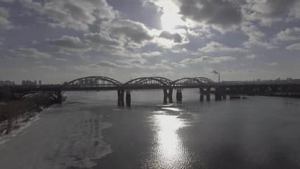 Aufkleber - Aerial view on the city with river in cloudy weather. Modern bridge in spring season. On the coat unmelted snow. Industrial cityscape.