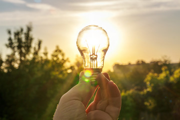 Wall Mural - The light bulb in her hand against the dawn.