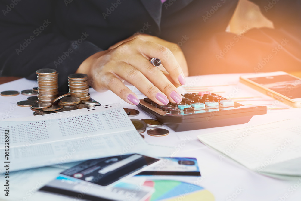 business woman hand analyzing financial data, account book,business graph with pile of coins ,stock chart and credit card background  - obrazy, fototapety, plakaty 