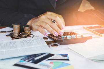 business woman hand analyzing financial data, account book,business graph with pile of coins ,stock chart and credit card background 