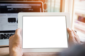 Hands holding tablet pc isolated white screen with laptop computer on wood table, using tablet mockup for advertising display and design