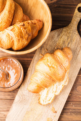 Fresh croissants with salted caramel on a brown wooden background, closeup, vertical, top view, selective focus
