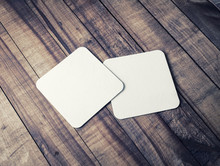 Two Blank Square Beer Coasters On Wood Table Background.