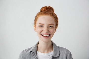 Wall Mural - Close-up view of pretty woman with red hair knot, blue charming eyes, freckles and gentle smile having delightful expression after good walk with her boyfriend. Happy female with appealing appearance