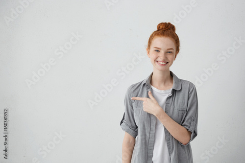 Smiling Red Haired Freckled Woman In Casual Shirt Posing Against