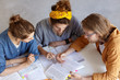 © WHstudio Leushin N - Portrait of two girl and one man sitting indoors studying reading books discussing main problems together being busy and overworked. Three college students doing research work. Teamwork conept