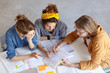 © WHstudio Leushin N - Group of pupils graduating from school preparing for their final exams meeting together learning material. Three friends having conentrated look in book pointing at it with pencils sitting indoor