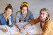 © WHstudio Leushin N - View from above of attractive girls and one bearded handsome guy in glasses sitting together at table surrounded with books being happy smiling in camera finishing their work rejoicing their results