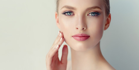 beautiful young woman with clean fresh skin touch own face . facial treatment . cosmetology , beauty