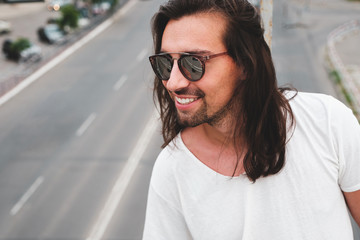 Wall Mural - Stylish hipster model with long hair lifestyle in the street. Dressed in a white T-shirt and torn blue jeans in the city