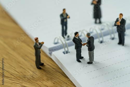 Fotografie, Obraz Miniature people with small figure businessmen handshaking and others clapping o