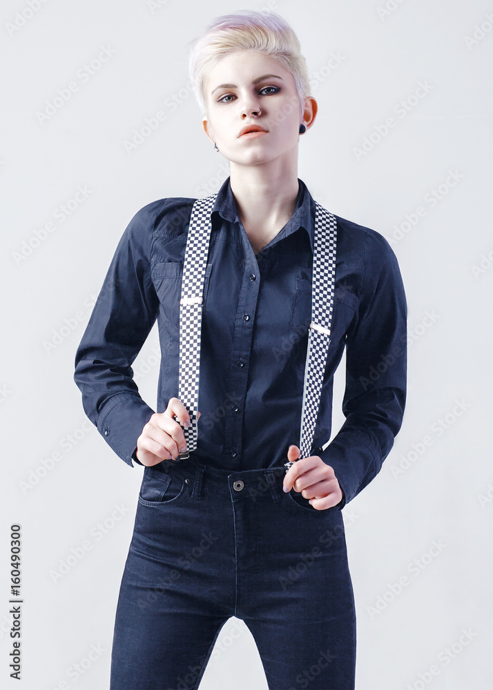 Elegant girl in black shirt and black jeans with suspenders on white background. Fashion photo. Studio portrait. Adobe Stock