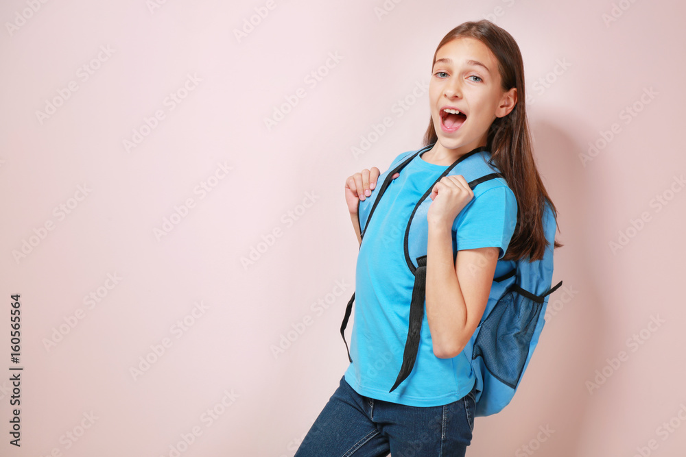 Cute pretty girl with schoolbag on color background