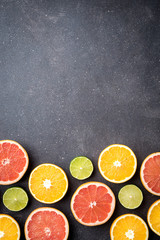 Wall Mural - Half of citrus fruits on dark stone background 