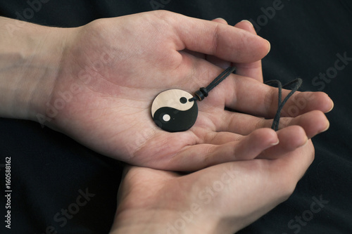 Plakat Dwa ręki trzyma perły yin Yang kolię na ciemnym tle.