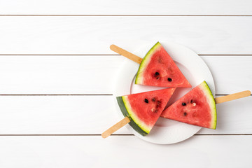 Wall Mural - Overhead shot of watermelon slices on white wooden background