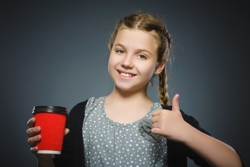 teenage girl offers red cup of coffee isolated on gray background