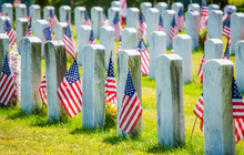 Rows Of Gravestones With American Flags In Military Cemetery