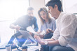 © SFIO CRACHO - Business partners meeting concept.Coworkers team working new startup project at modern office.Analyze business documents, using touch tablet.Blurred background.Horizontal