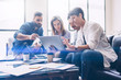 © SFIO CRACHO - Concept of presentation new startup project.Group of young coworkers discussing ideas with each other in modern office.Business people using electronic devices.Horizontal, blurred background.