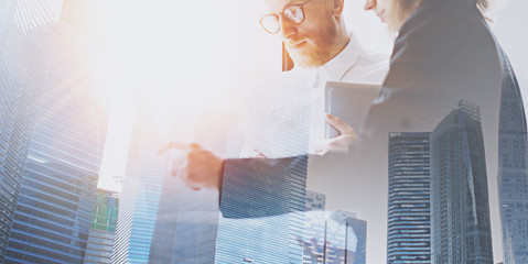 Wall Mural - Young coworkers on meeting at the office place.Business team in working process.Double exposure,skyscraper building blurred background.Flares effect